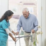 Home healthcare worker helping elderly man with walker
